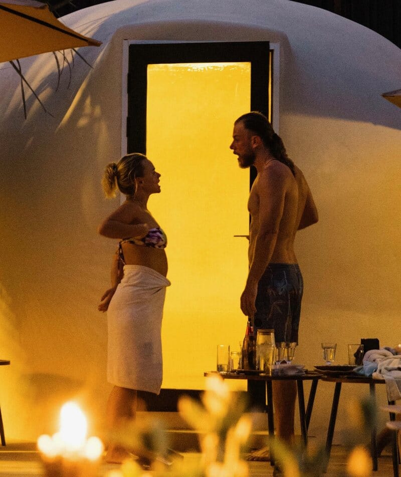 The steam dome lit from within at dusk, two bathers at its door