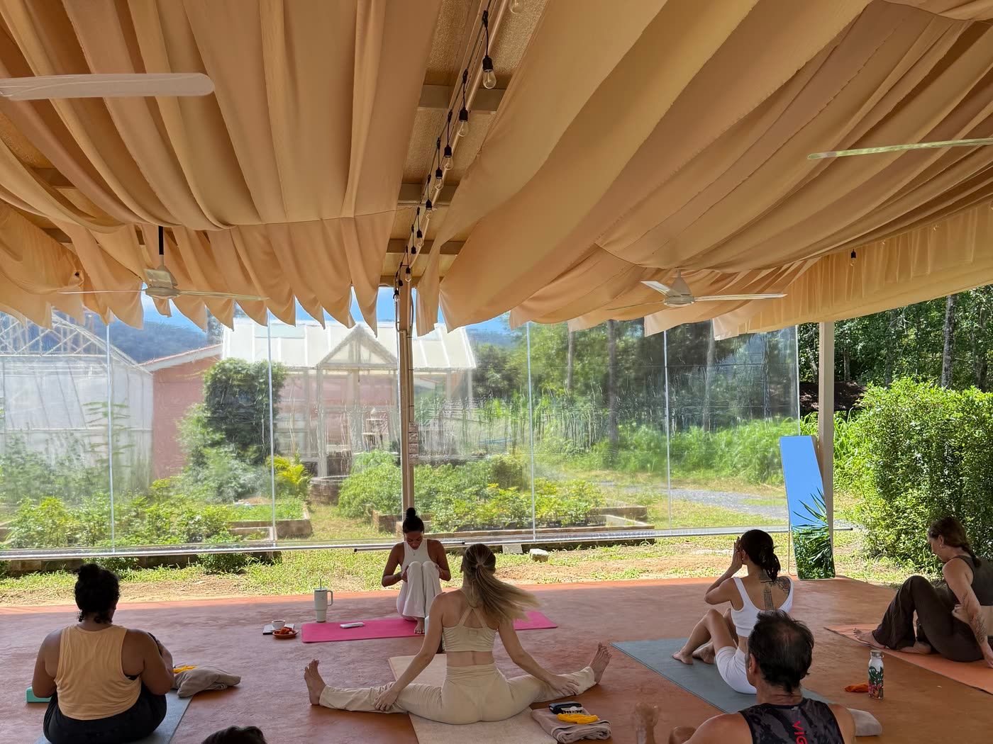 The open-air yoga shala at Rustic & Blue, with the greenhouse and hills behind